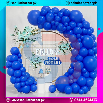 Blue balloon arch with 'Enjoy every moment' sign in a decorated room.