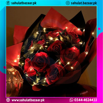 Bouquet of red roses with LED lights wrapped in black paper, on a dark background.