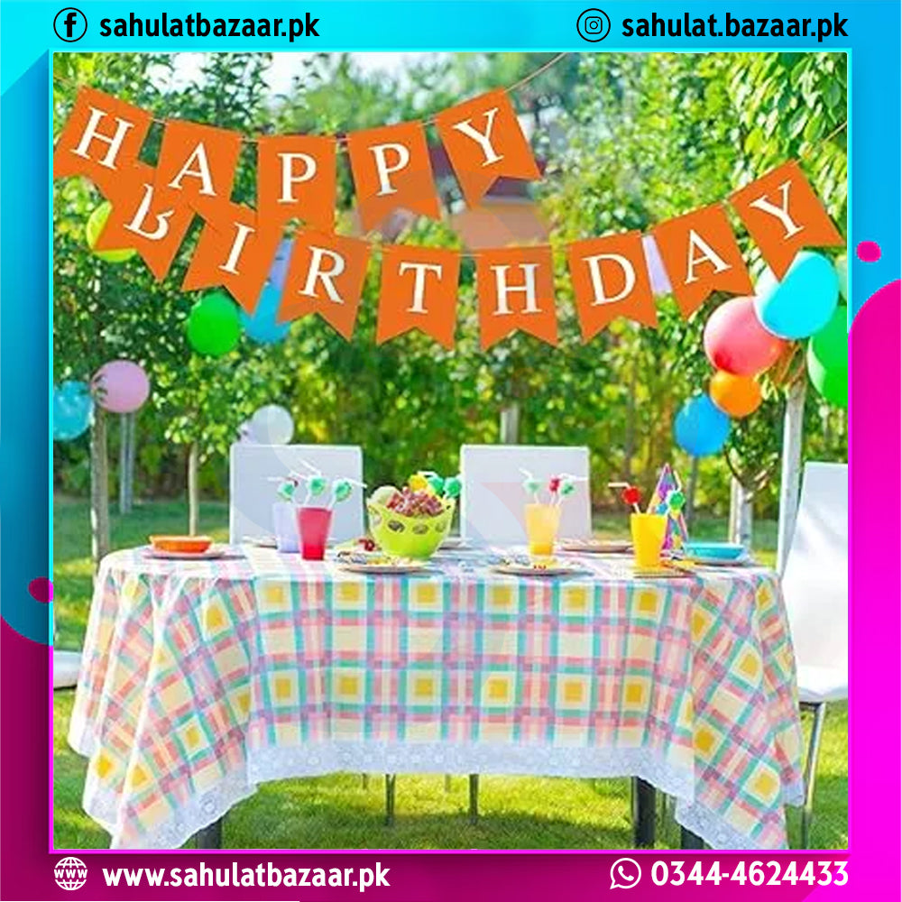 Birthday celebration setup with a 'Happy Birthday' banner, tableware, and balloons outdoors.