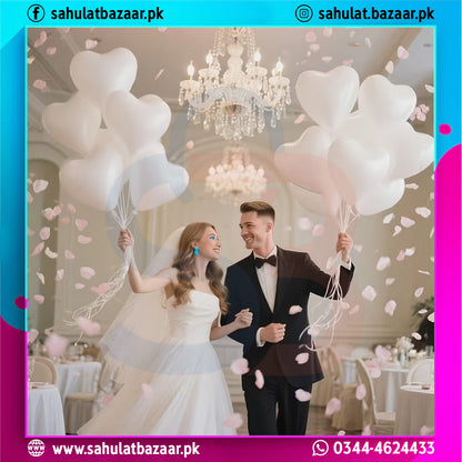 Couple holding heart-shaped balloons in a decorated room with chandeliers.